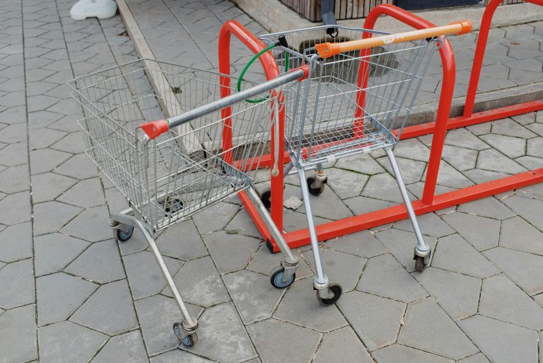 Shopping trolleys attached to metal stand near supermarket on street